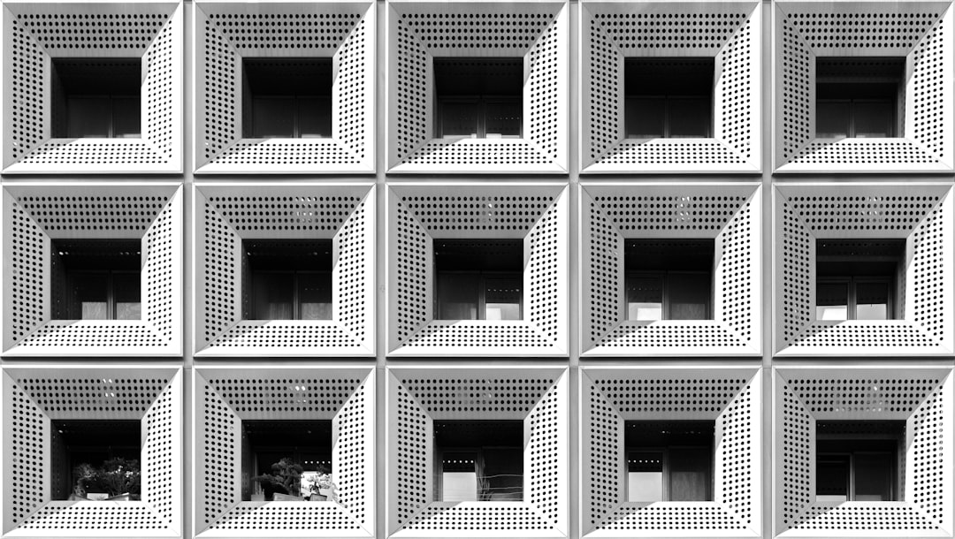 Professional investor carefully examining a detailed architectural model of a modern building in a bright, sunlit office, ...