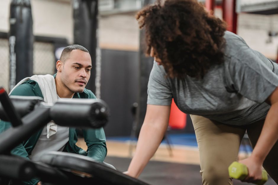 A personal trainer works one-on-one with a client in a modern, bright gym, representing the sustained, long-term partnership of an SEO retainer.