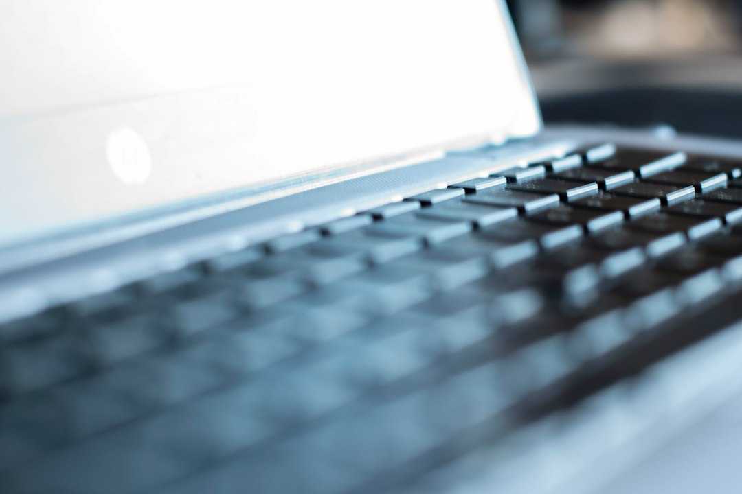 Close-up of modern house keys resting on a sleek laptop keyboard, symbolizing the intersection of technology and the real ...